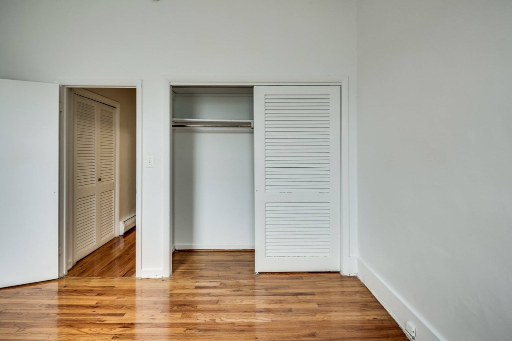 a bedroom with a closet and a hard wood floor