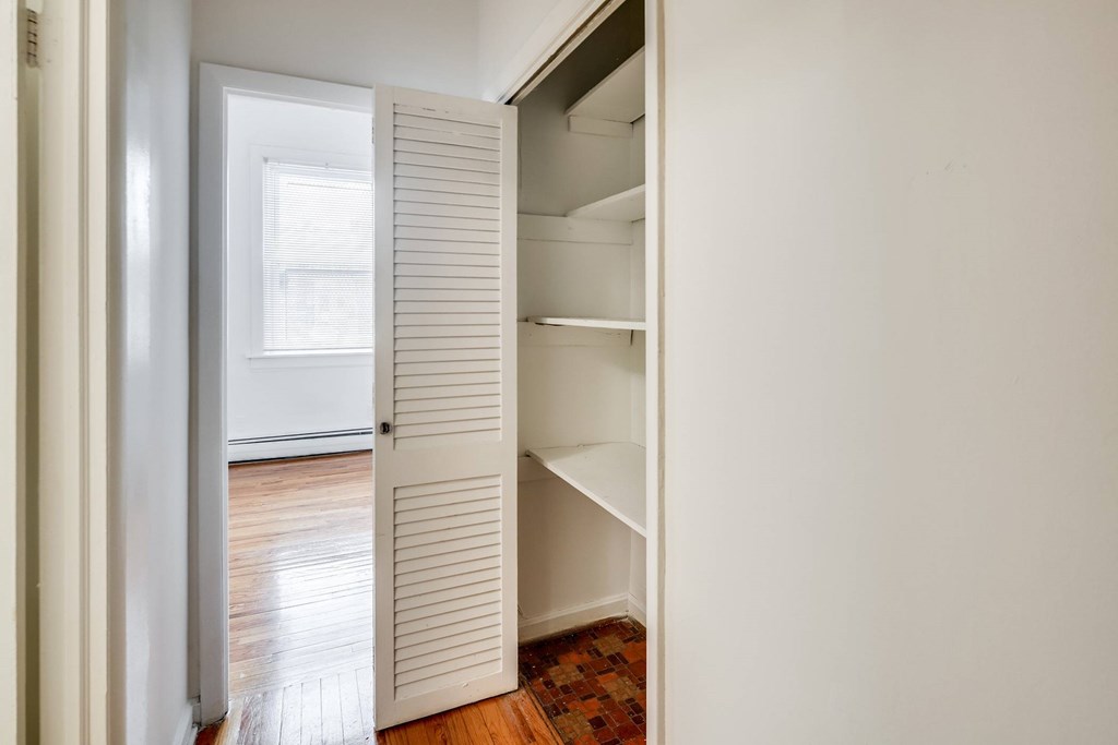 a closet in a bedroom with a window and wood floors