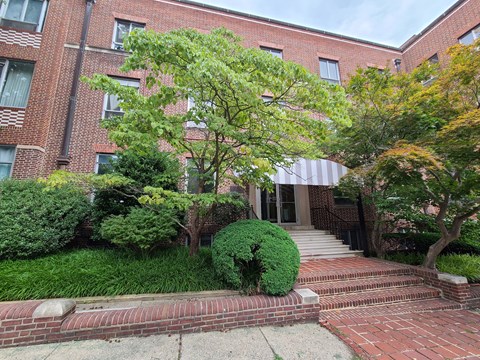 A red brick building with a tree in front of it.