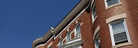 the side of a brick building with windows and a roof