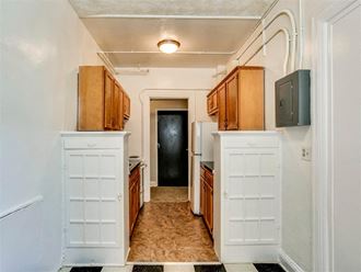 a kitchen with white cabinets and a door to a hallway