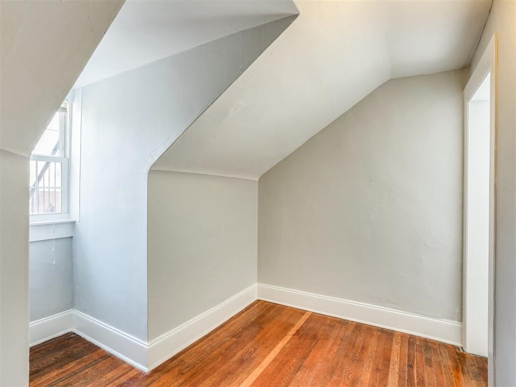 an empty room with white walls and wooden floors and a window