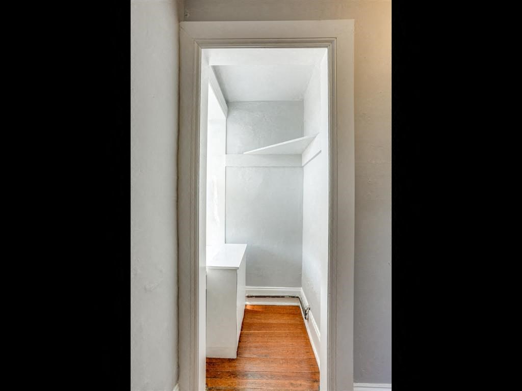 a small room with an empty closet and a wood floor