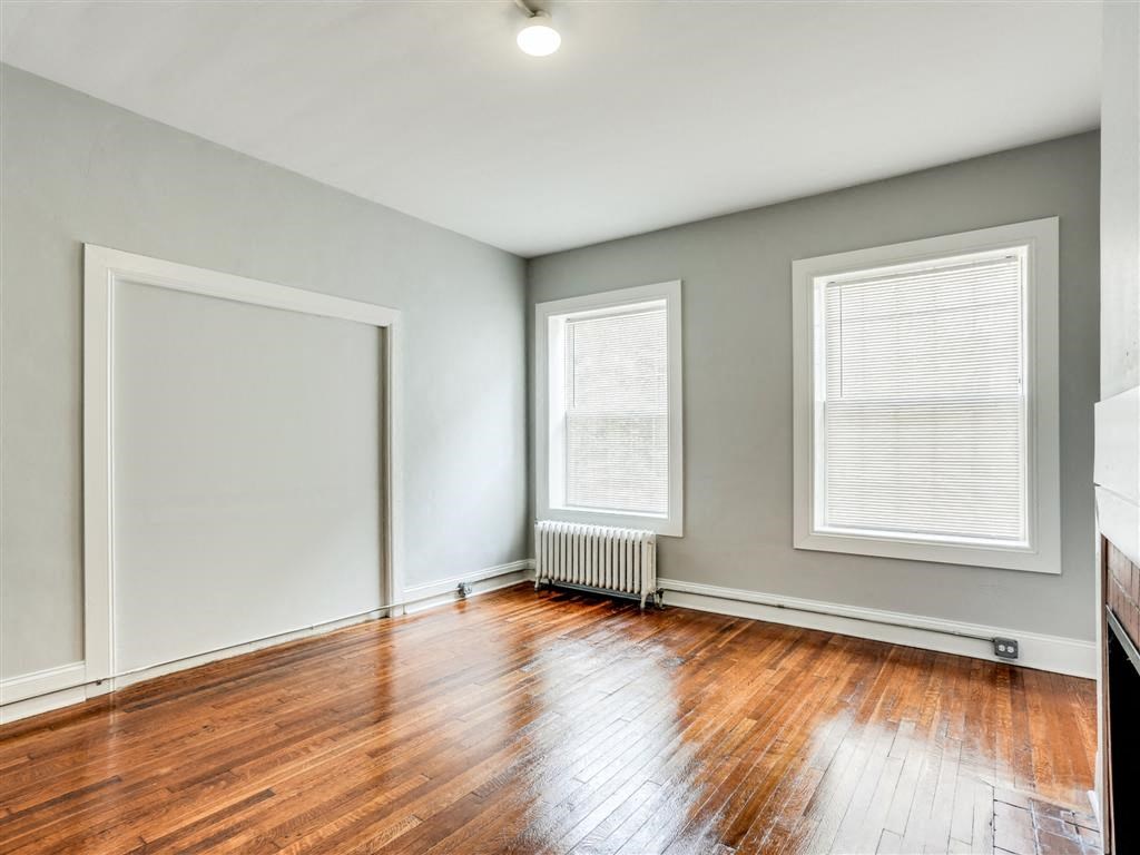 an empty room with wood floors and two windows