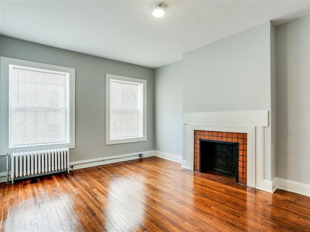 an empty living room with a fireplace and wooden floors