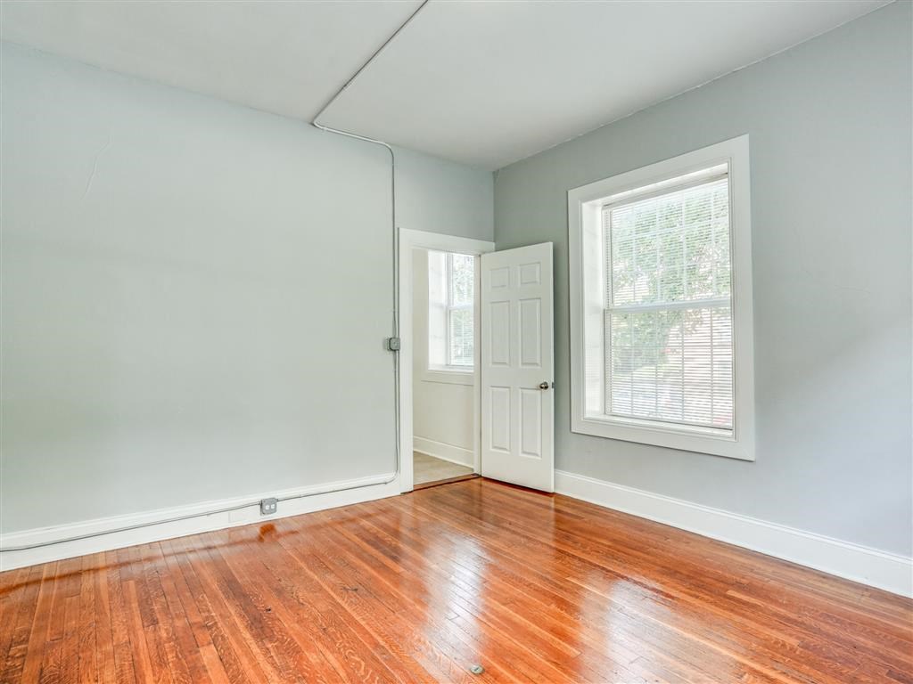 an empty room with wood floors and a door and window