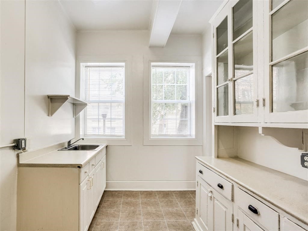 a kitchen with white cabinets and a sink and a window