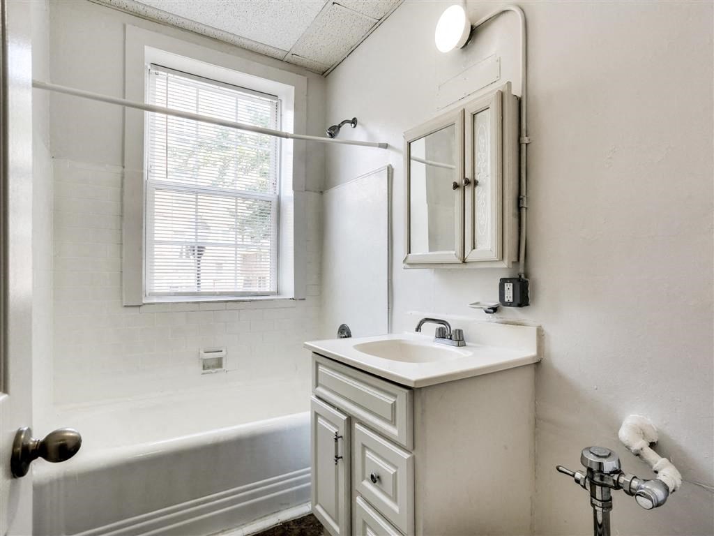 a white bathroom with a sink and a bath tub
