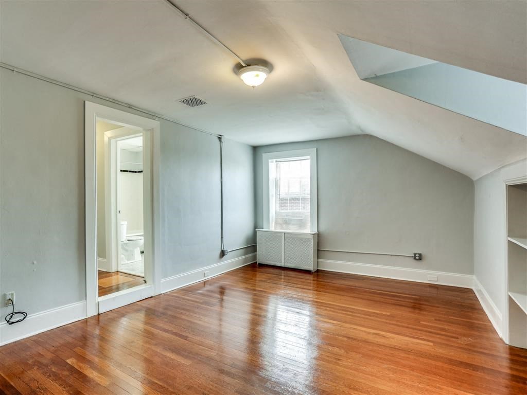 an empty living room with wood floors and a window