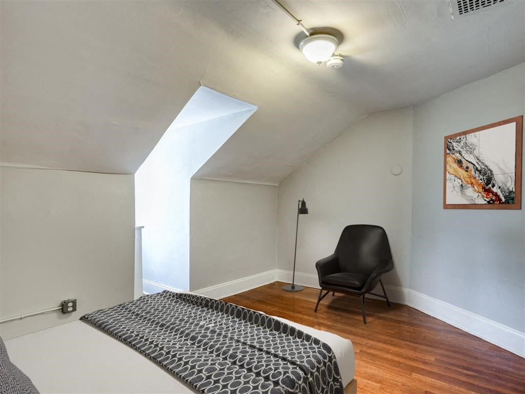 a bedroom with a bed and a chair in the corner