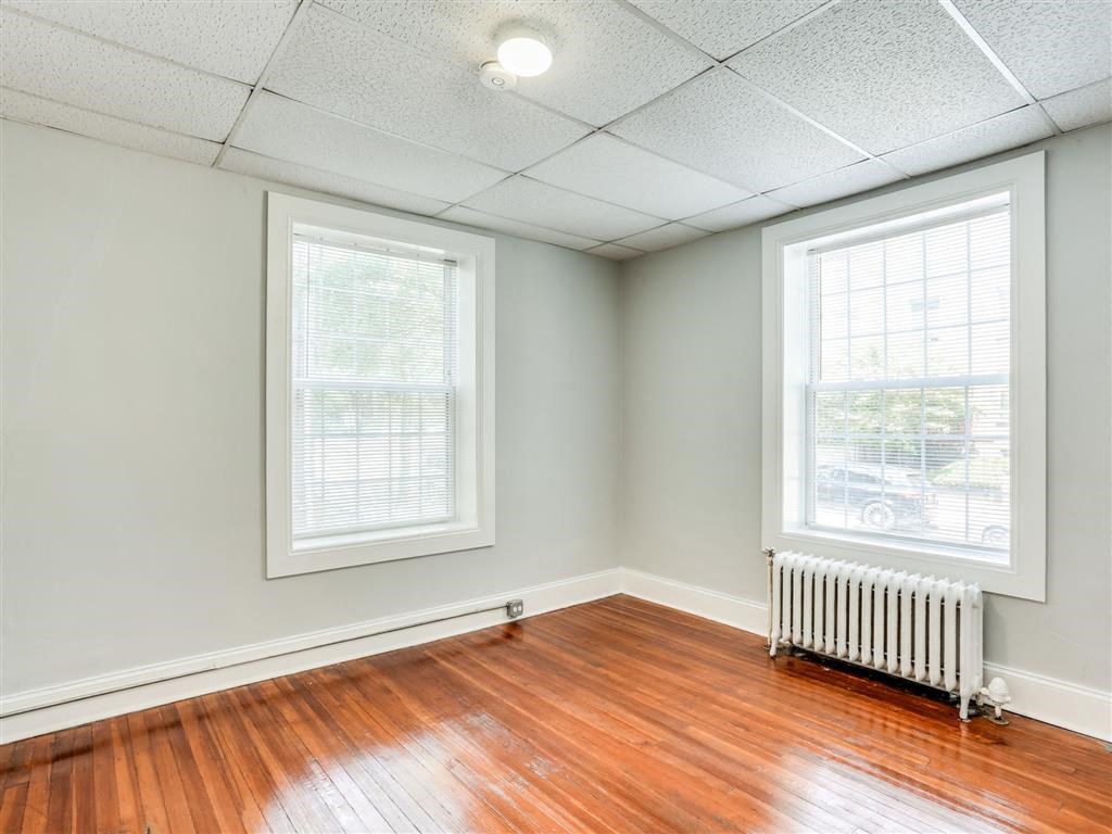 an empty room with wood floors and two windows