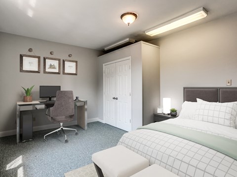 A bedroom with a bed, desk, and chair.