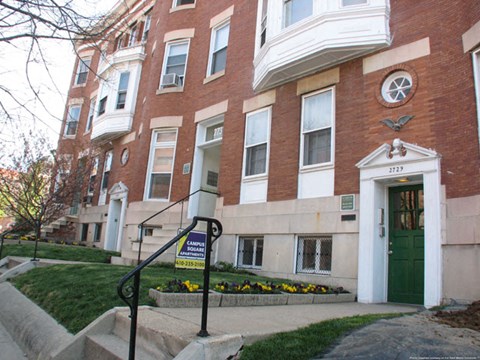 a red brick building with a green door and stairs