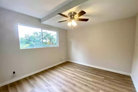 an empty living room with a ceiling fan and a window