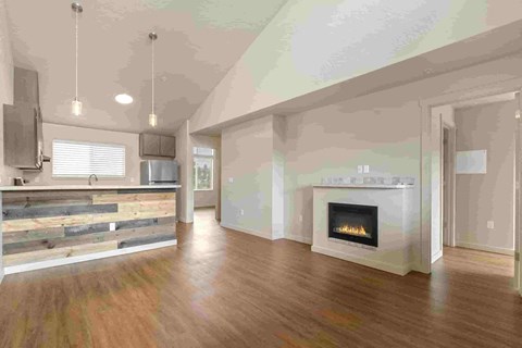 an empty living room with a fireplace and a kitchen