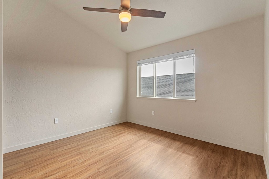 A room with a ceiling fan and a window with blinds.