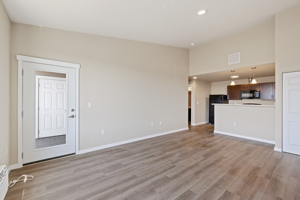 an empty living room and kitchen with wood flooring