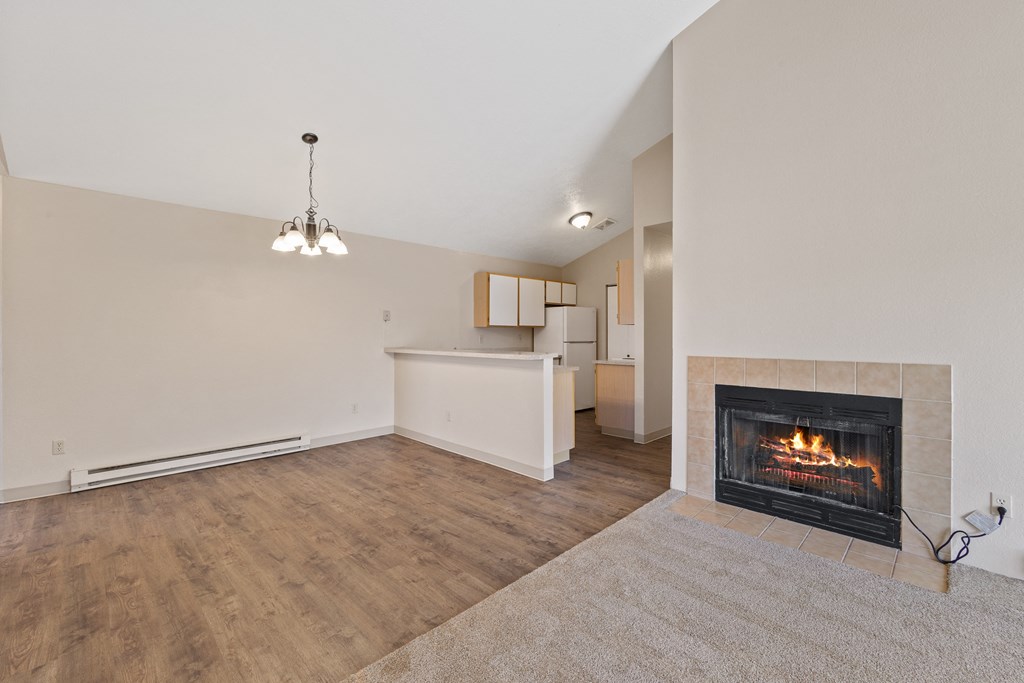 an empty living room with a fireplace and a kitchen
