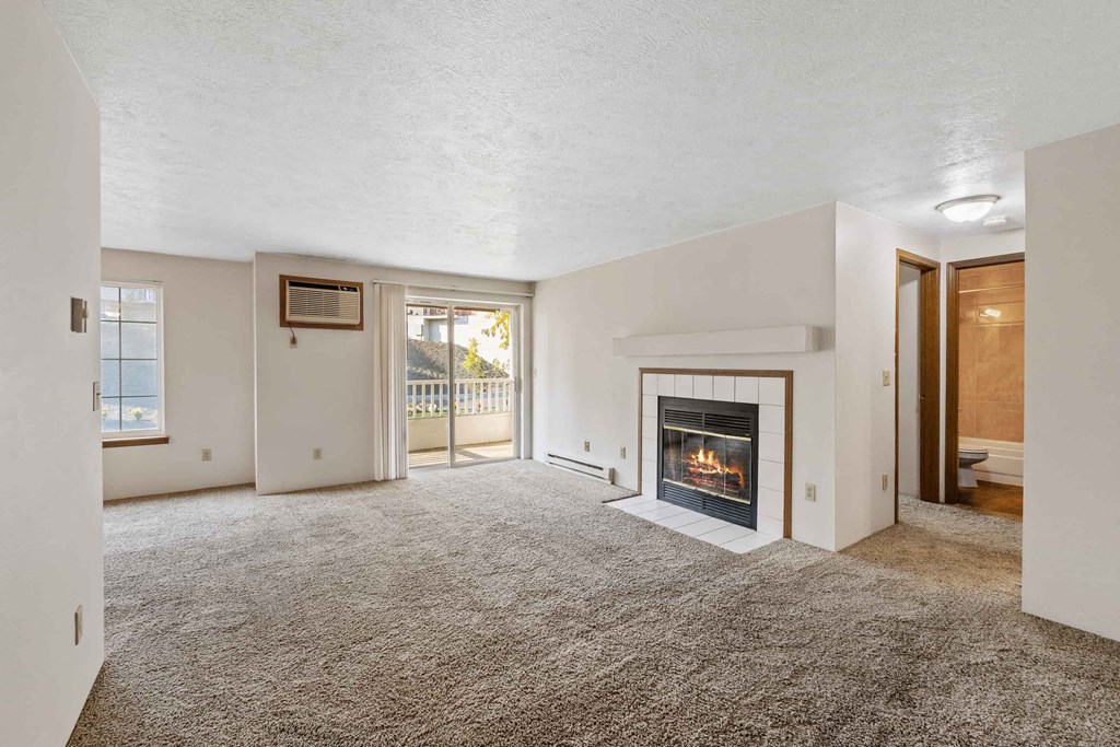 a living room with a fireplace and a door to a balcony
