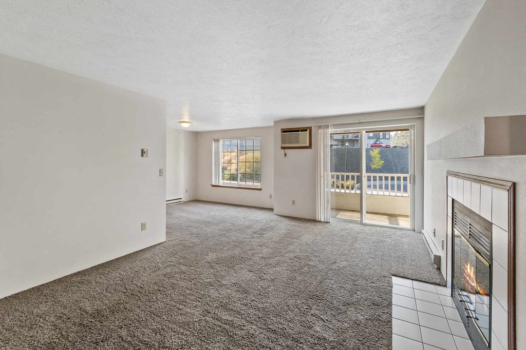 an empty living room with a fireplace and a door to a balcony