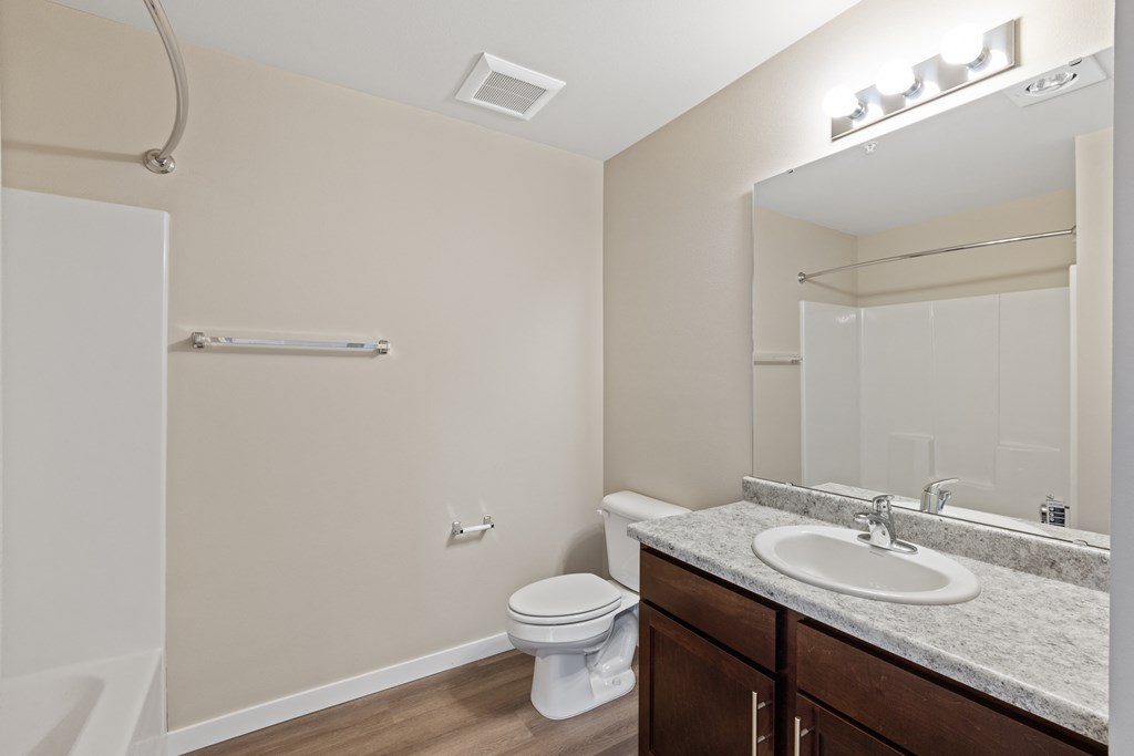 a bathroom with a toilet sink and mirror and a shower