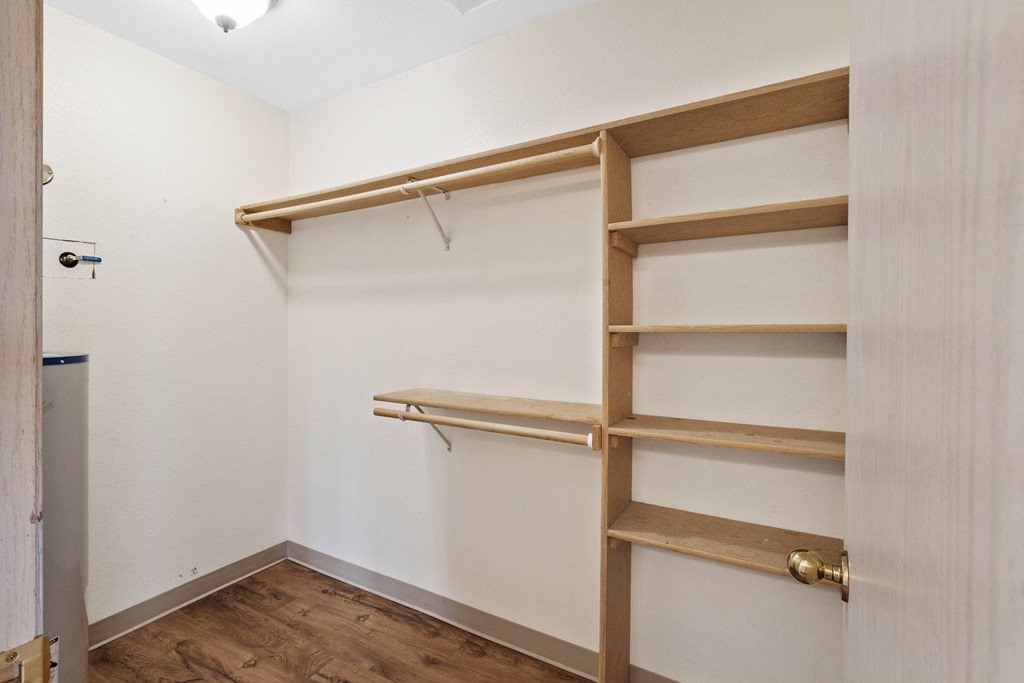 a walk in closet with wooden shelves and a door