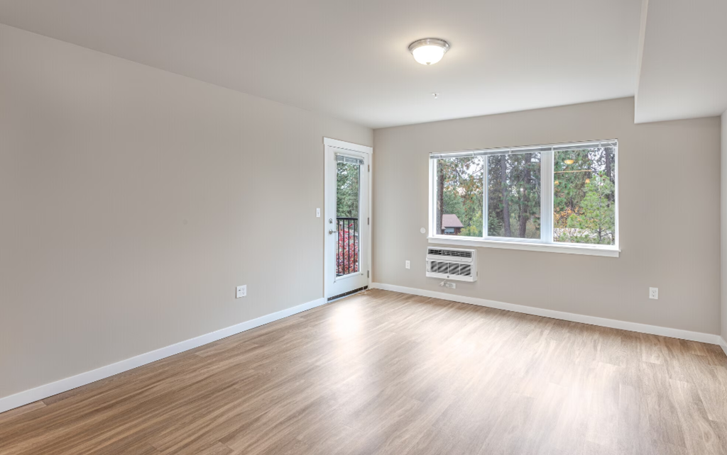 an empty living room with wood floors and a window
