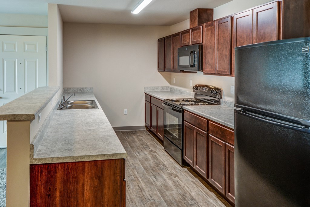 an empty kitchen with wooden cabinets and stainless steel appliances