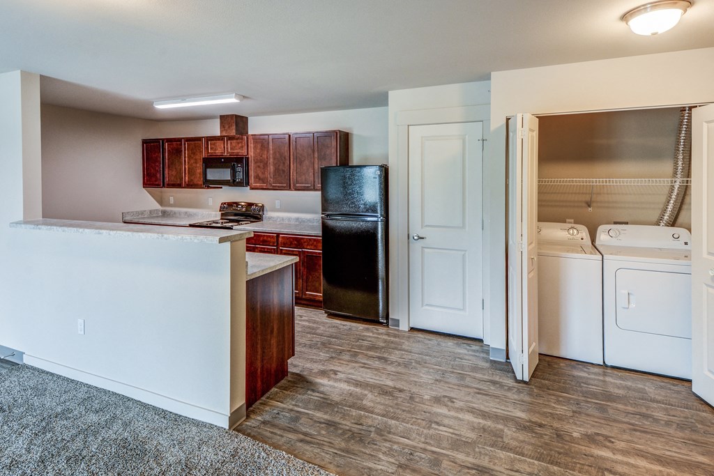 an empty kitchen with a washer and dryer and a refrigerator