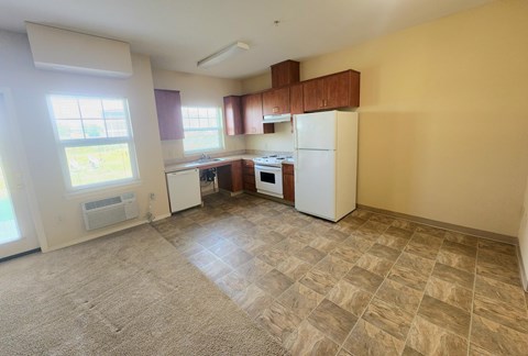 A kitchen with a white refrigerator and a window with blinds.