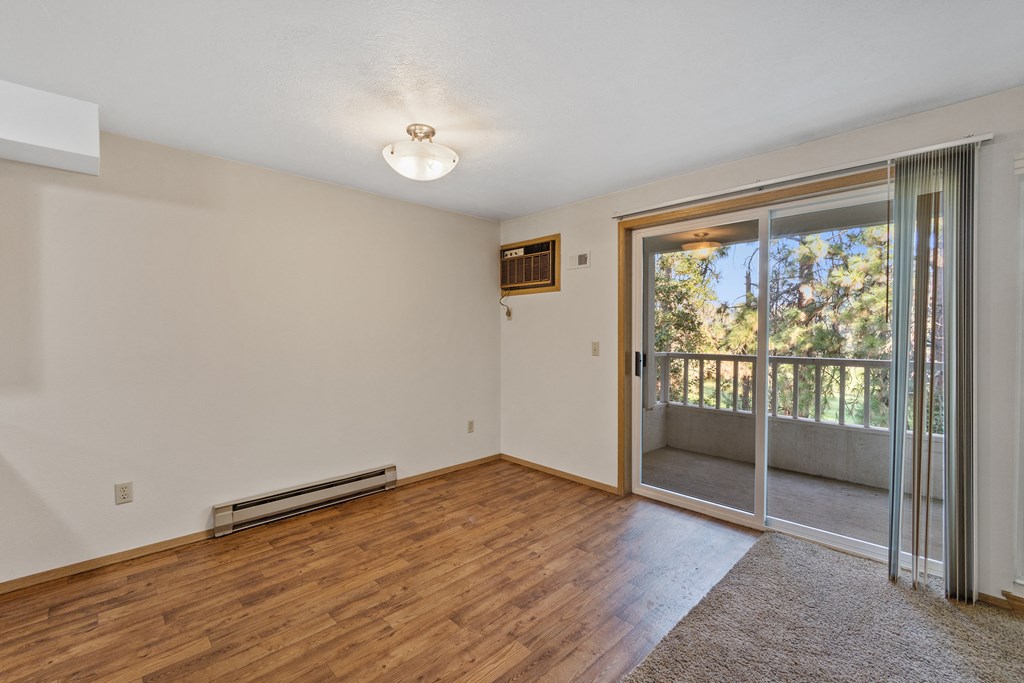 an empty living room with a sliding glass door to a balcony