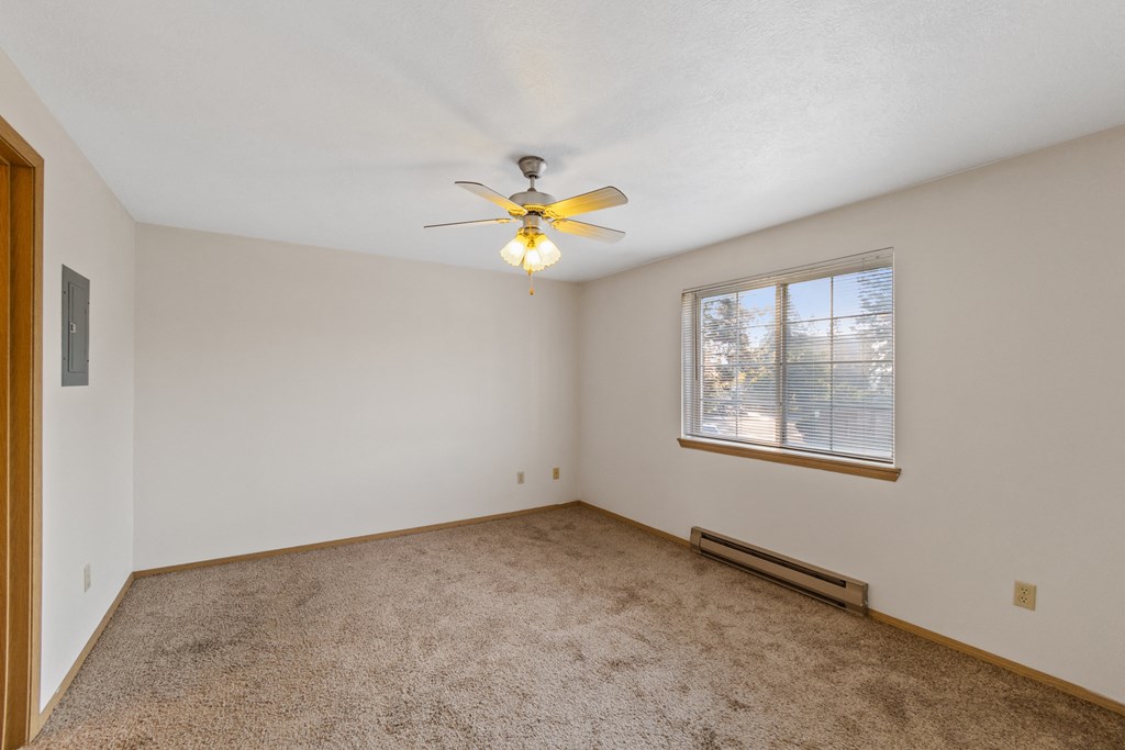 an empty living room with a ceiling fan and a window