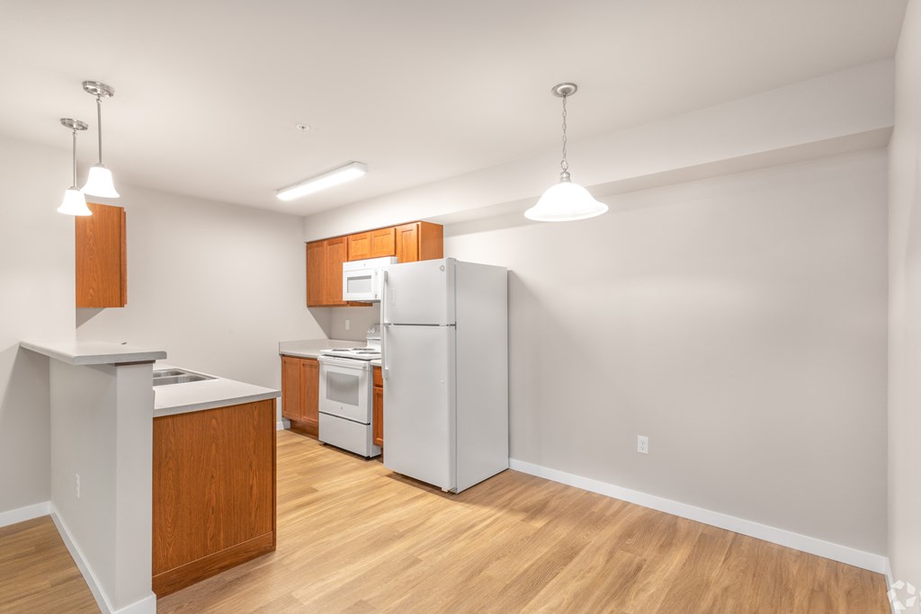 a kitchen with white appliances and wood flooring and a refrigerator