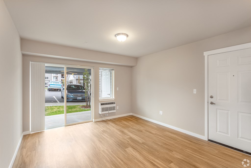 an empty living room with wood floors and a door to a street