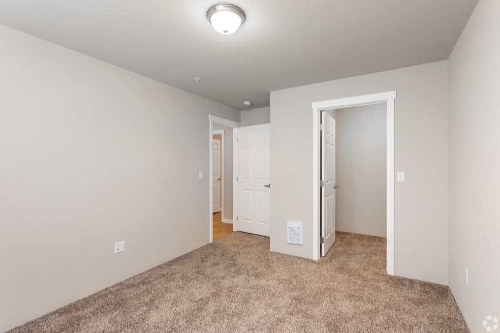 a living room with carpet and a door to a bedroom