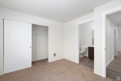 a bedroom with a door to a bathroom and a closet