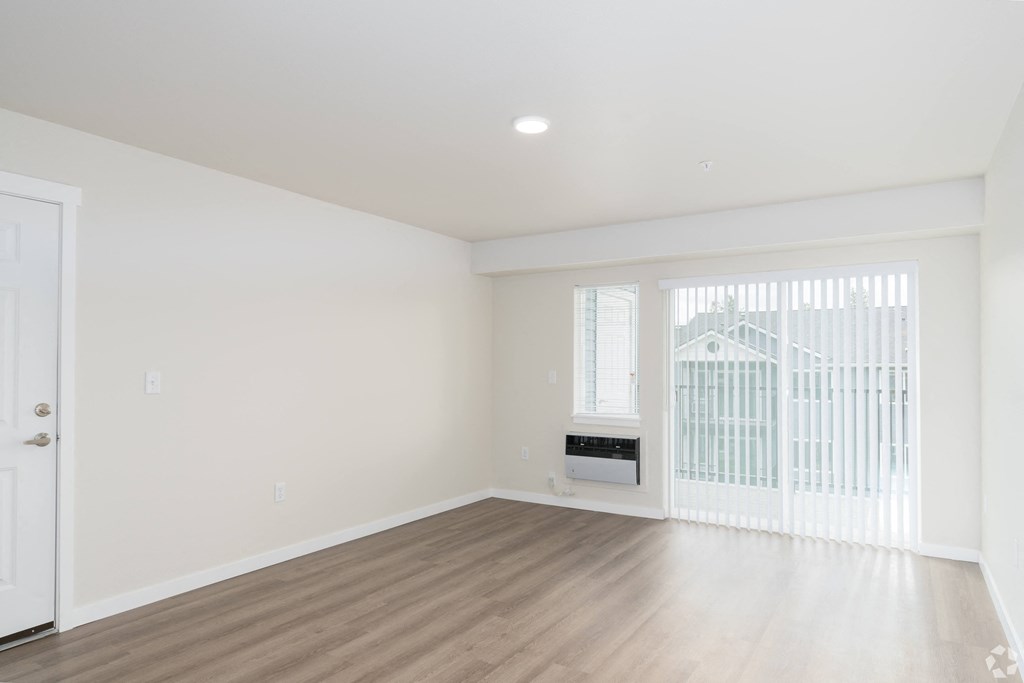 an empty living room with white walls and a window with a radiator and a door