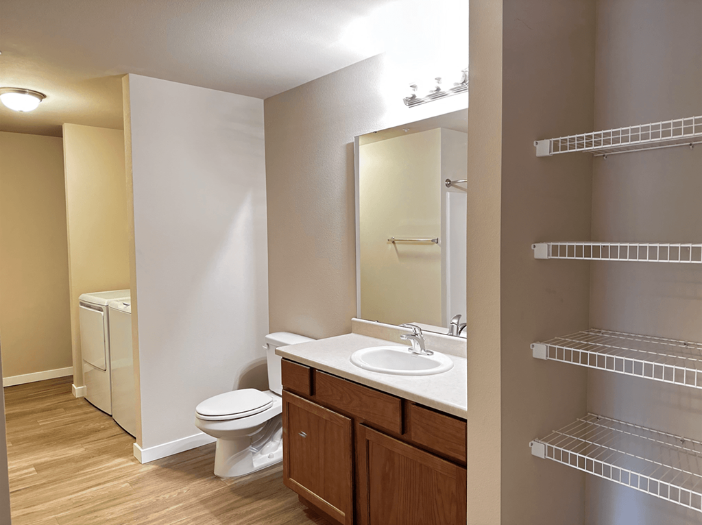 A bathroom with a toilet, sink, and mirror.
