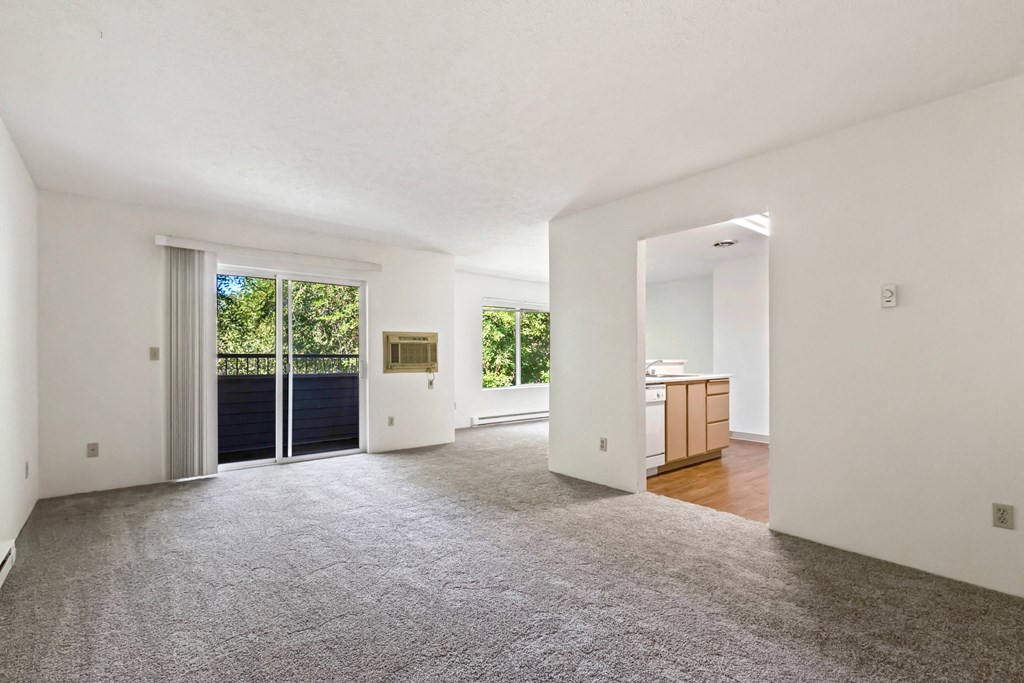 a living room with a door to a kitchen and a carpeted floor