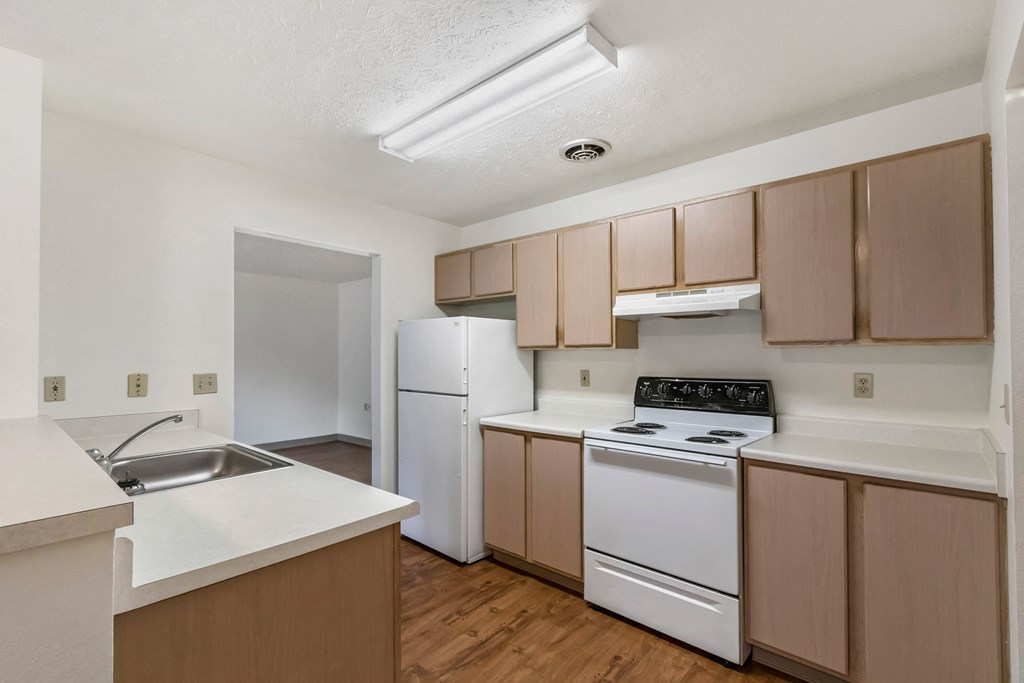 an empty kitchen with white appliances and wooden cabinets