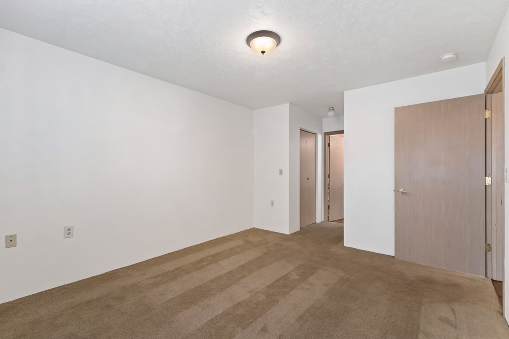 an empty living room with white walls and a door to a hallway