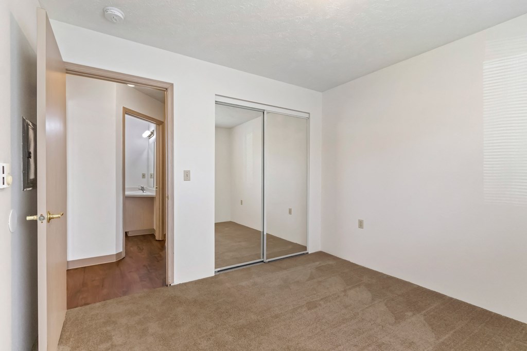 an empty living room with a sliding glass door to a bathroom