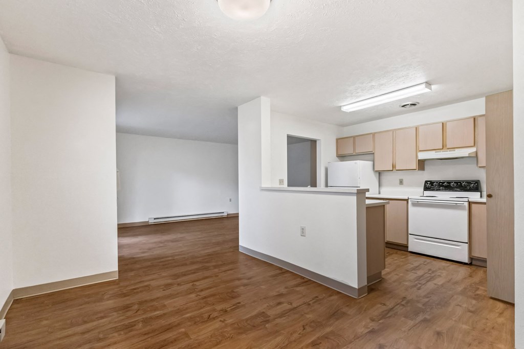 A kitchen with white appliances and wooden floors.