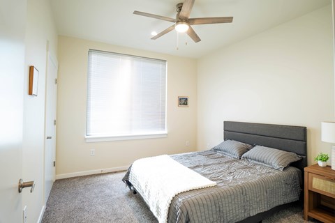 A bedroom with a bed, nightstand, and window.