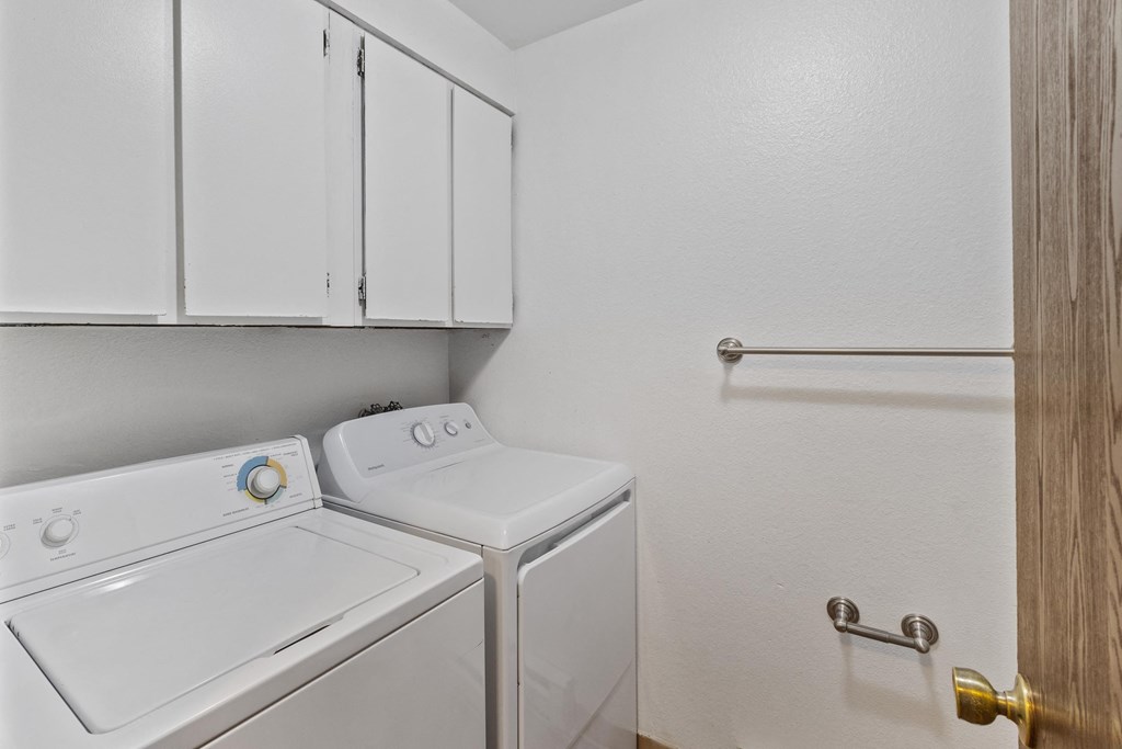 a laundry room with a washer and dryer and white cabinets