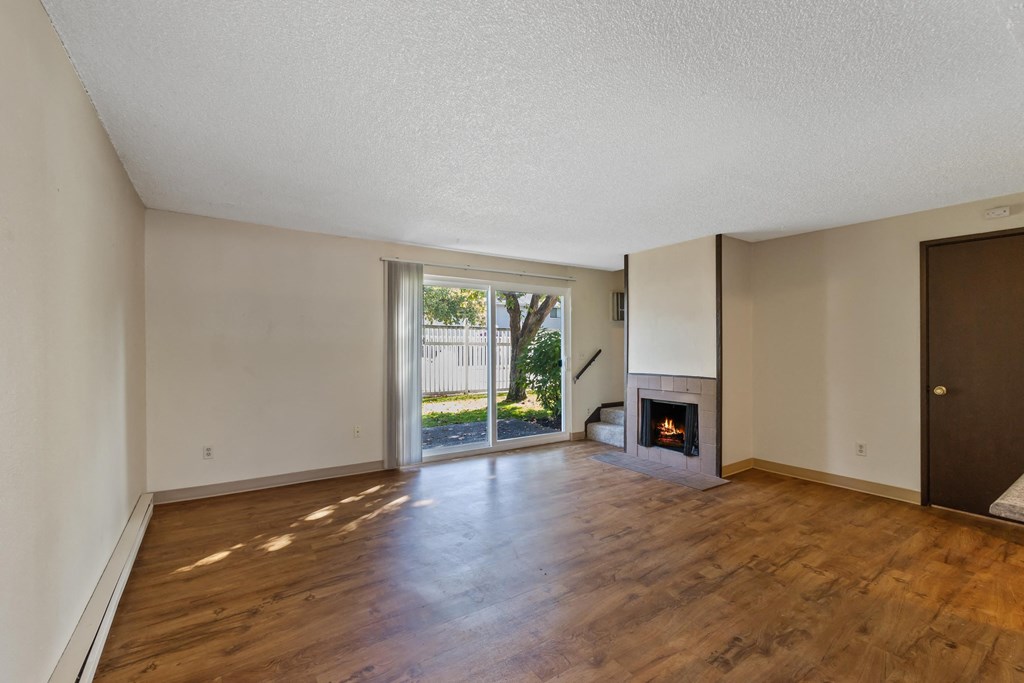 an empty living room with a fireplace and wooden floors