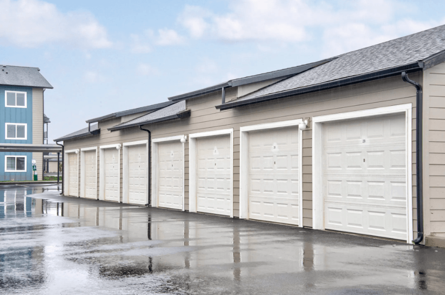 a row of garages with white doors in a parking lot