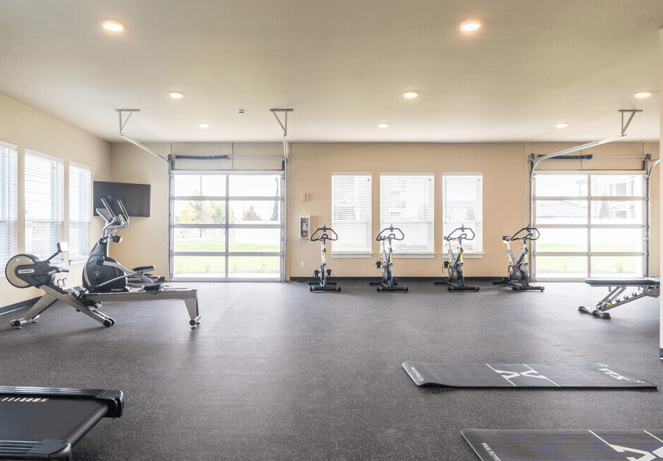 a gym with treadmills and weights on the floor and windows