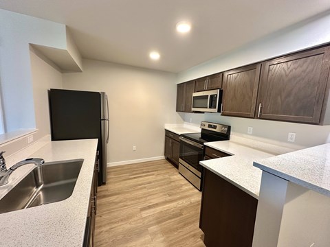 A kitchen with brown cabinets and a black refrigerator.
