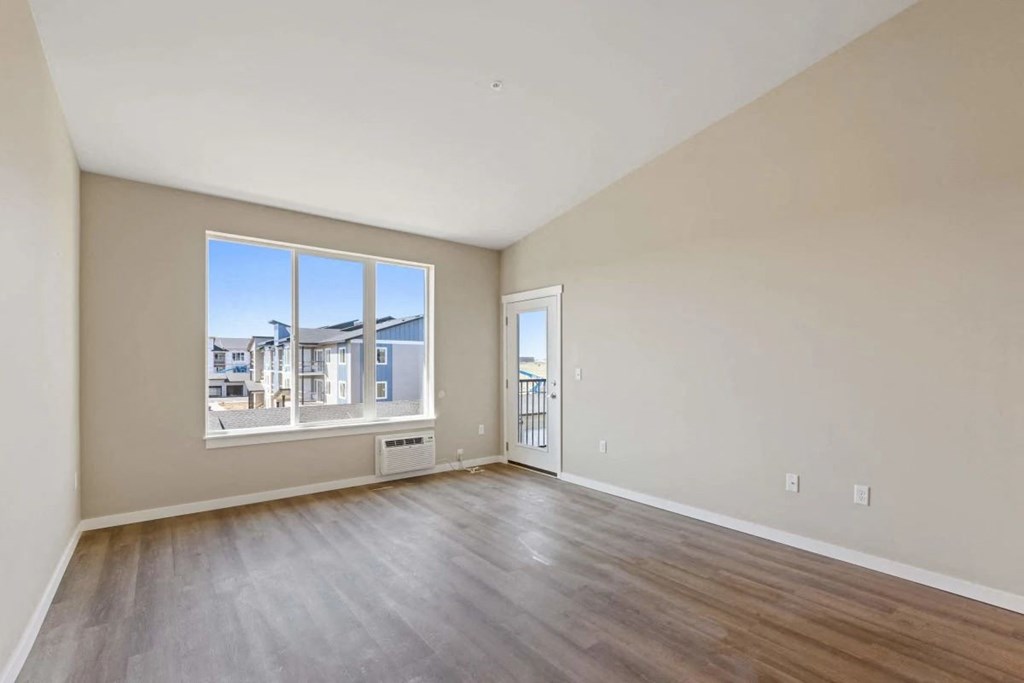 an empty living room with a large window and wooden floors